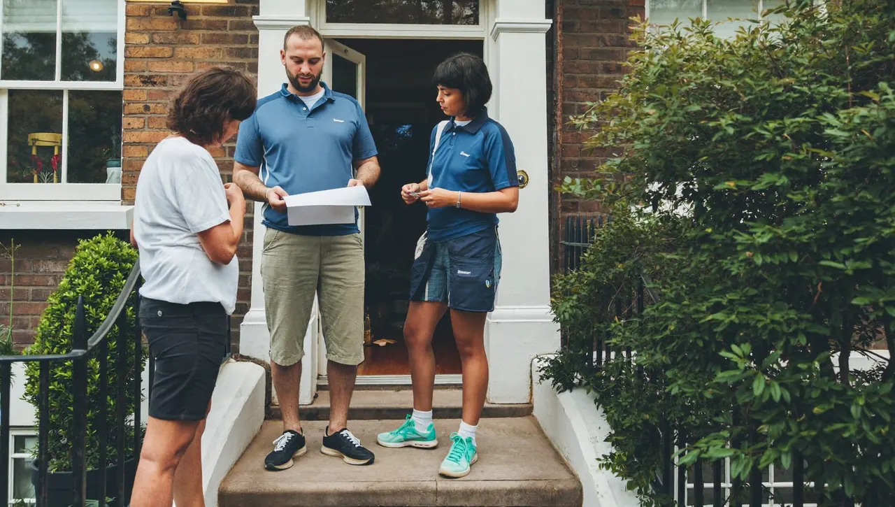 Installer explaining a window quote to a homeowner on the doorstep